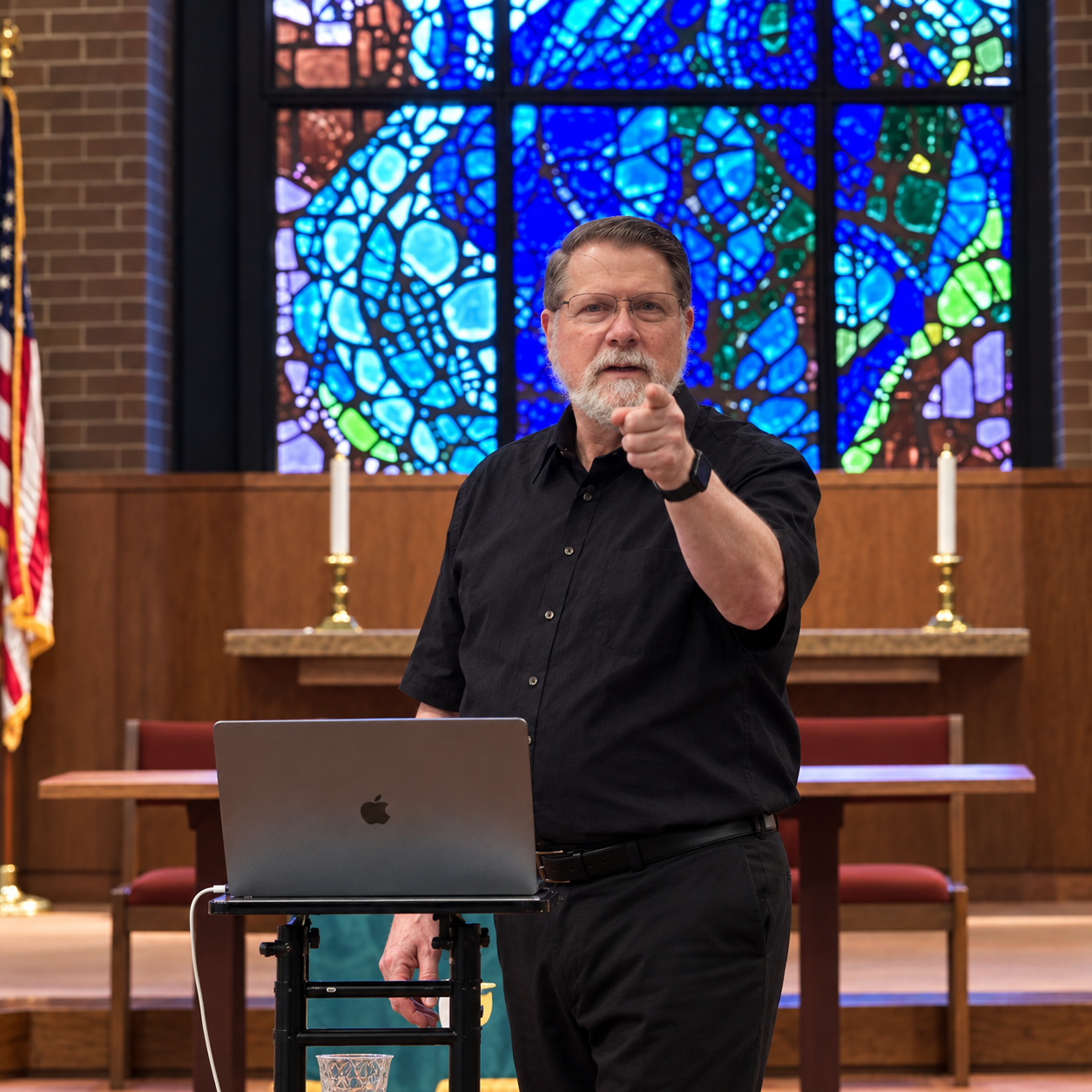 Bill Tenny-Brittian teaching in a church sanctuary beneath stained-glass windows